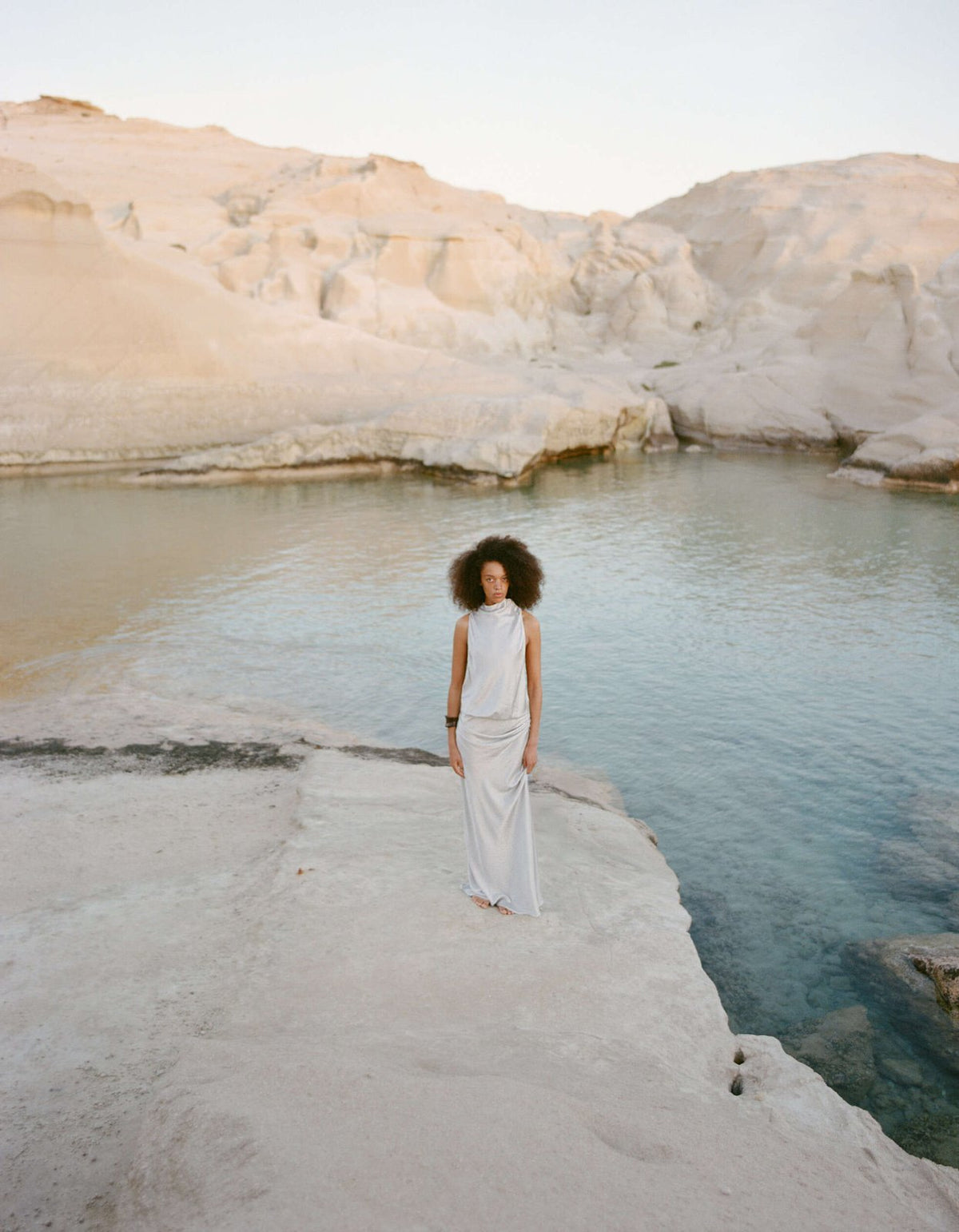 Bec and Bridge Juna Maxi Dress in Silver worn on coastal rocks